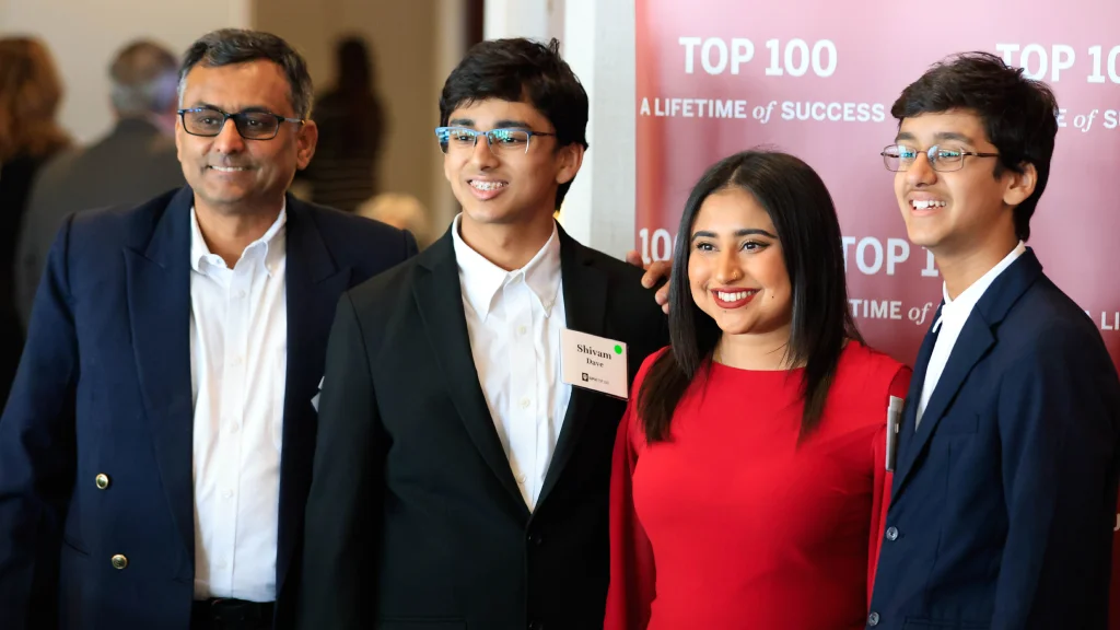 A family in formal wear pose for a photo with their Top 100 awardee at an IU Indianapolis ceremony.