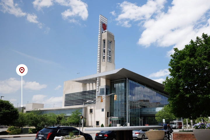 Cars are parked along the street in front of the Campus Center. A white circle with red indicator points to to a garage behind and to the left of the Campus Center when looking northwest.