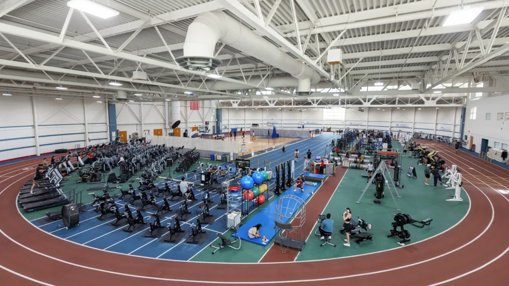 Indoor fitness center with cardio and strength equipment, surrounded by a running track.