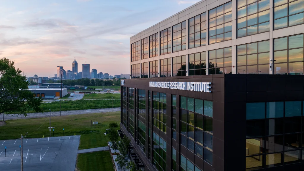 Indiana Biosciences Research Institute building with modern glass exterior and a backdrop of the Indianapolis city skyline.