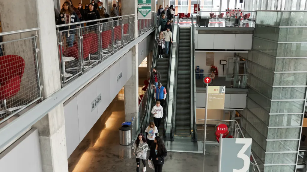 Visitors to campus descend an escalator in the Campus Center atrium.