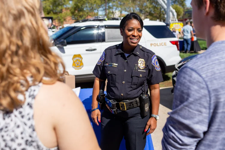 A police officer stands smiling and speaking with attendees at Regatta.
