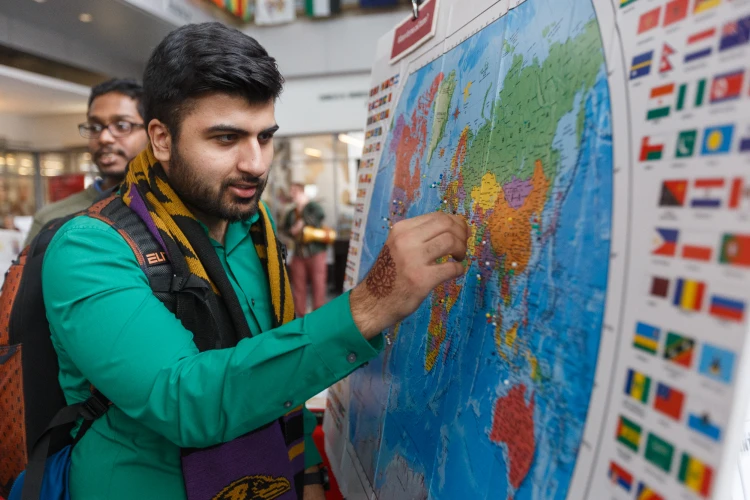 A student placed a pin on a world map flanked with international flags on display in the Campus Center.