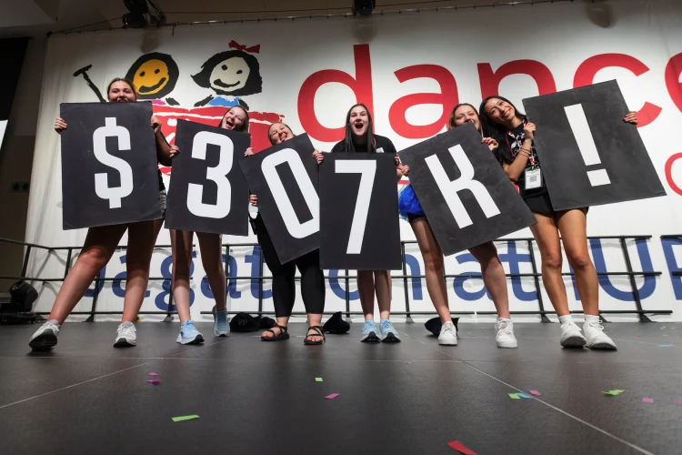 Six students in a link hold up black posters that spell out $307K!, the total raised for the Jagathon dance marathon that year.