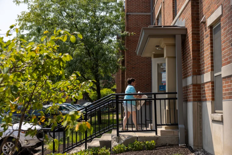 A person walks up a short set of stairs to a door of Riverwalk apartments.