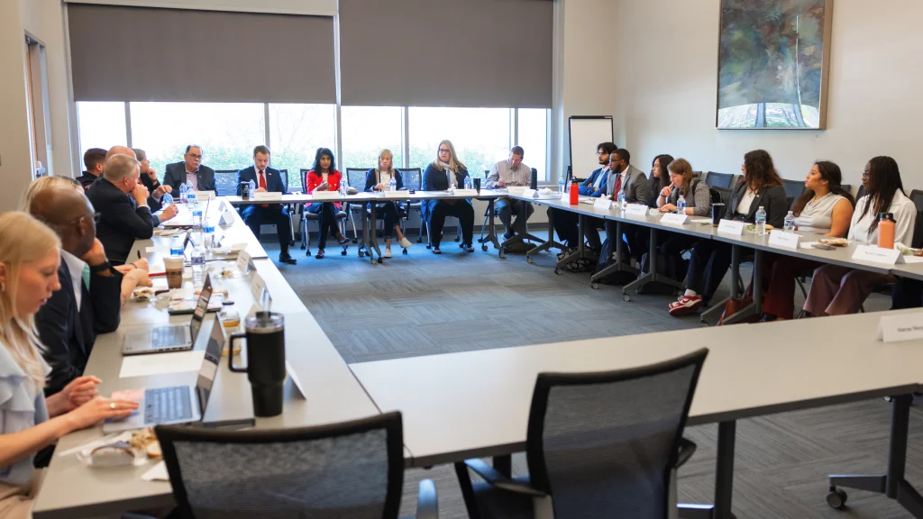 Students and members of campus leadership sit around a tables arranged in a large rectangle for an advisory board meeting.