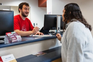 A student speaks to a staff member over the public counter at the University College Advising Center.