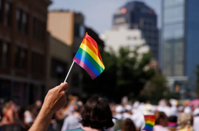 A hand holds up a rainbow flag along the Pride Parade route in downtown Indianapolis.